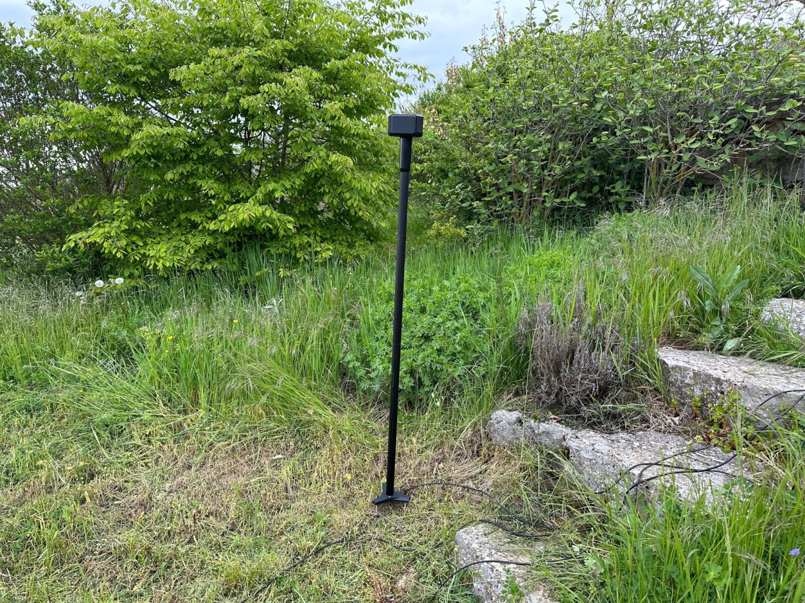 Image de l'antenne GNSS installée dans un jardin verdoyant, montrant son utilisation dans le guidage précis du robot tondeuse EcoFlow Blade