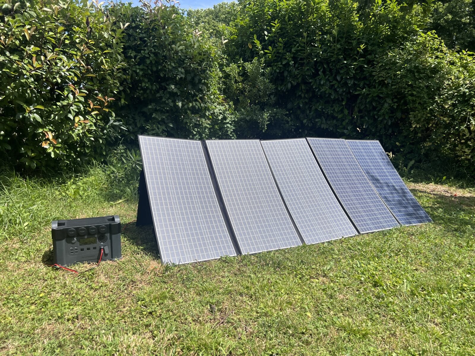 Batterie ALLPOWERS S2000 Pro et panneau solaire installés côte à côte dans un champ verdoyant