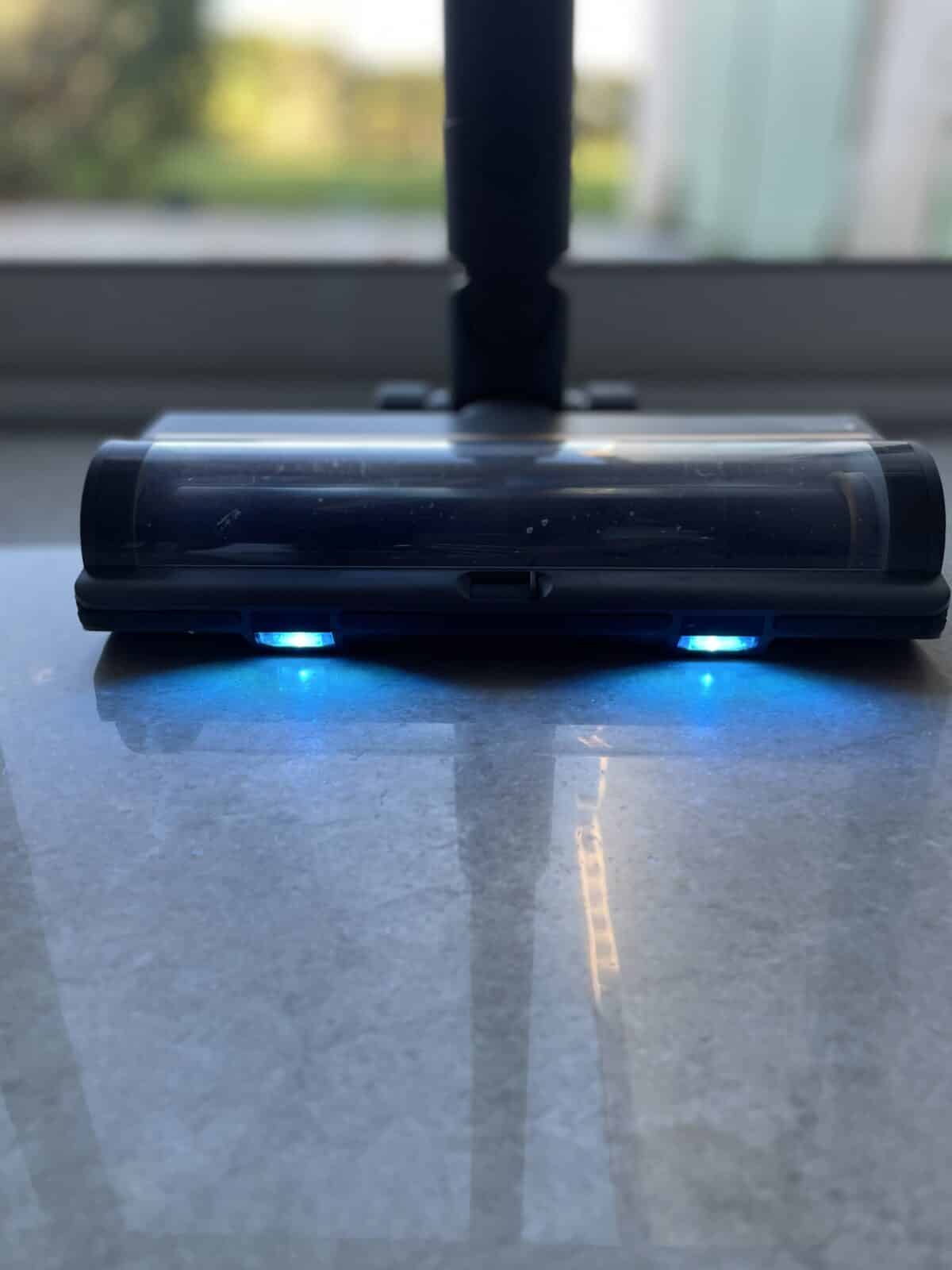 Fonctionnalité de la lumière LED bleue du Dreame R20 éclairant la poussière sur le sol pour une meilleure visibilité