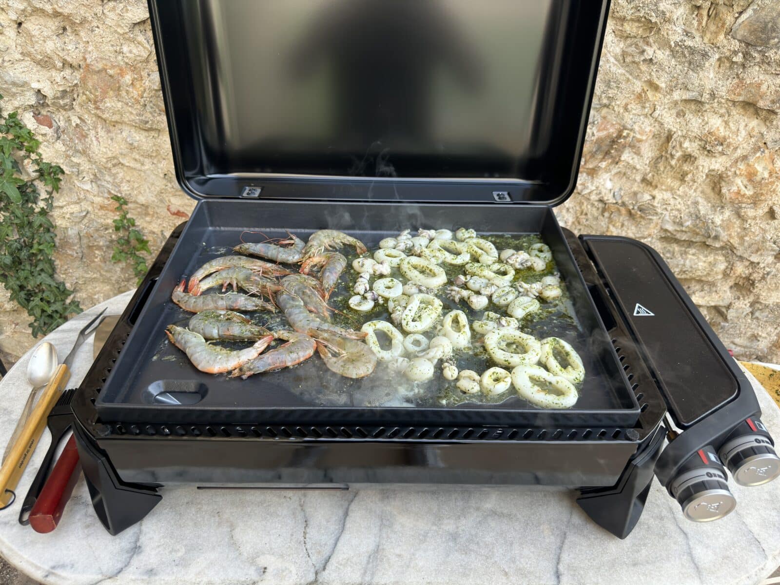 Plancha en cours de cuisson avec divers aliments prêts à être servis