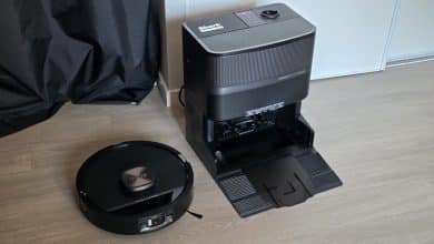 Le robot Shark PowerDetect UV Reveal posé au sol devant sa grande base d'auto-vidange noire