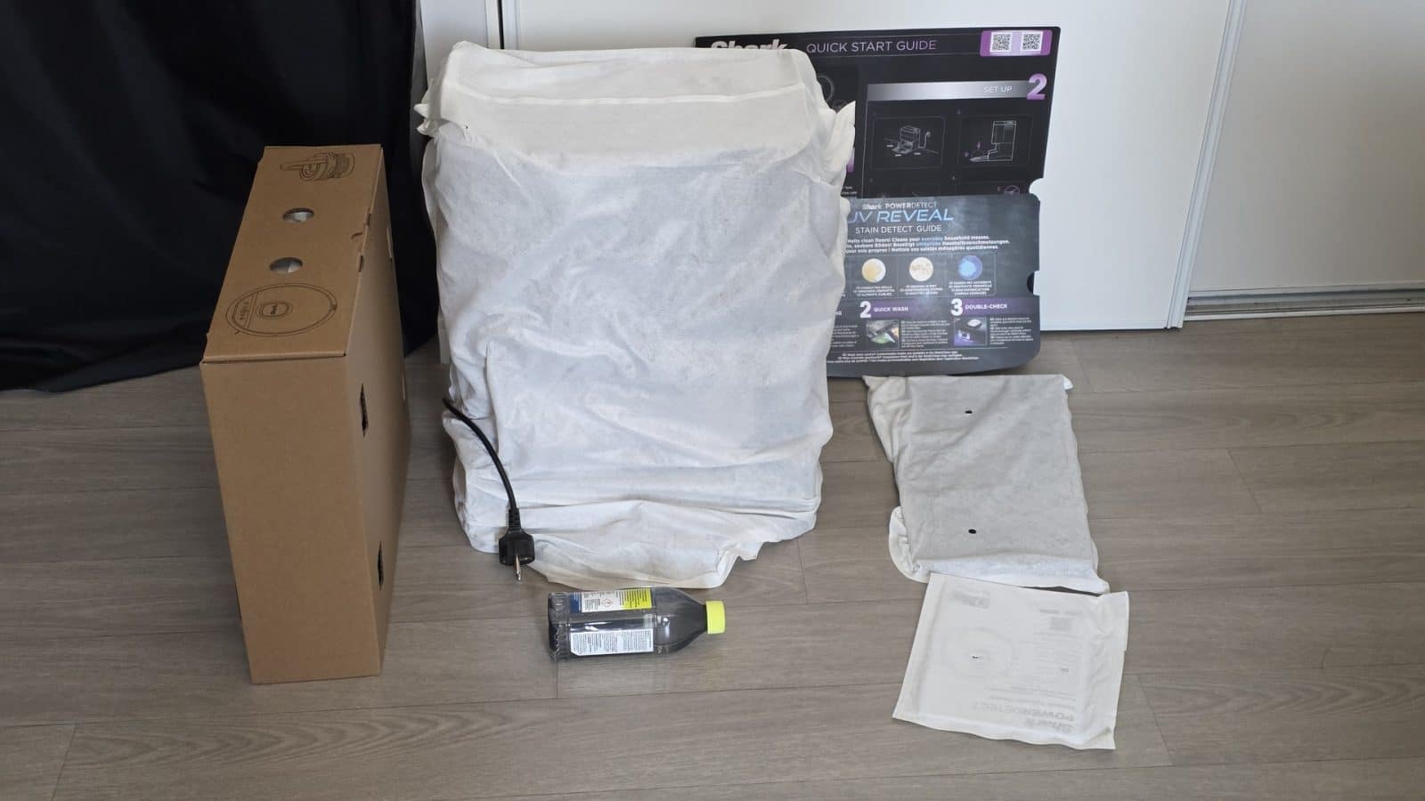 Déballage du Shark PowerDetect UV Reveal : carton, robot sous housse, guide de démarrage et flacon de solution nettoyante