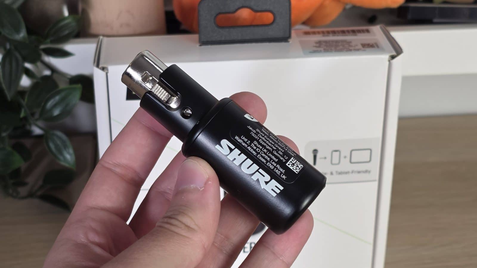 Interface Shure MVX2U Gen 2 tenue en main devant sa boîte
