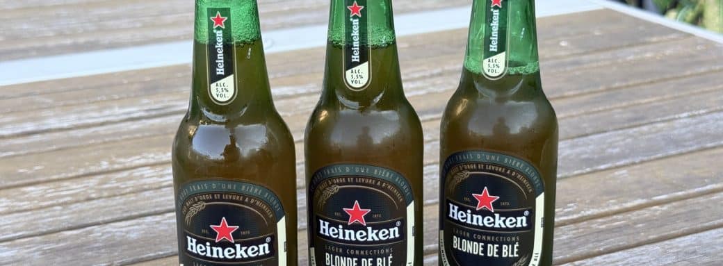 Trois bouteilles de Heineken Blonde de Blé sur une table de jardin