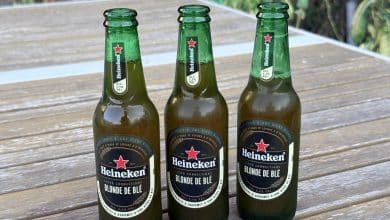 Trois bouteilles de Heineken Blonde de Blé sur une table de jardin