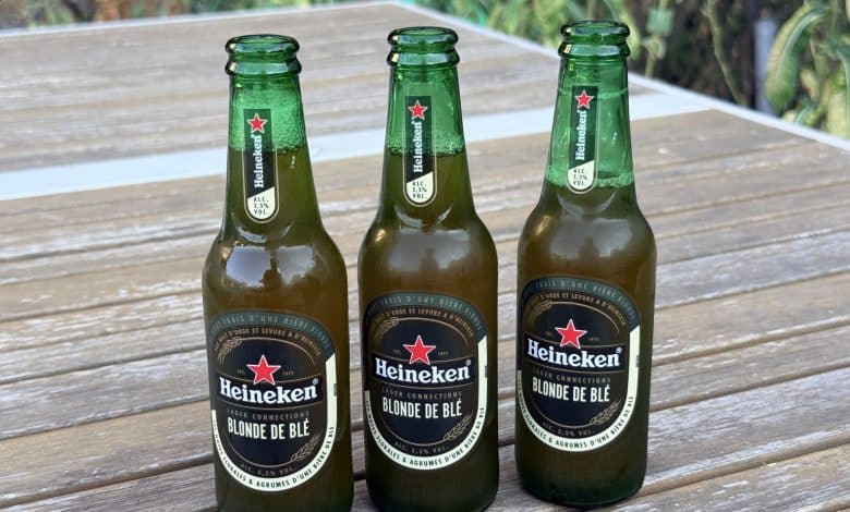 Trois bouteilles de Heineken Blonde de Blé sur une table de jardin