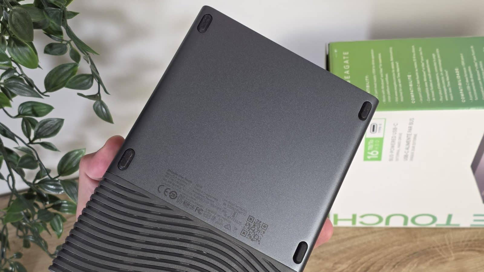 Dessous du Seagate One Touch tenu en main, avec ses patins et ses mentions réglementaires