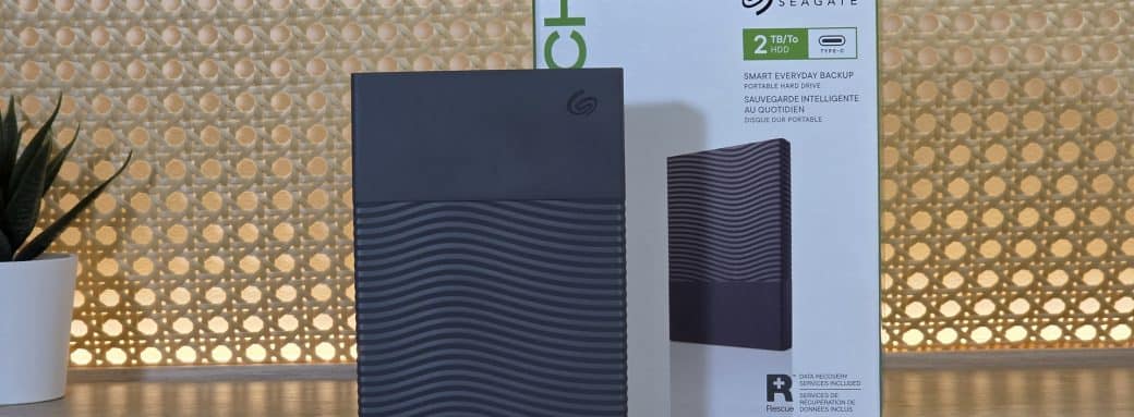 Disque dur portable Seagate One Touch 2 To gris posé debout devant sa boîte sur un bureau